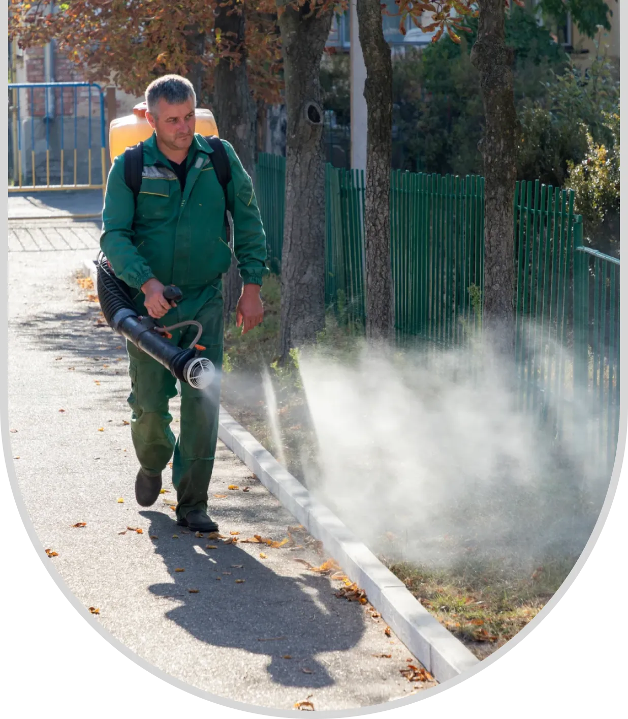 A man spraying water from a hose on the sidewalk.